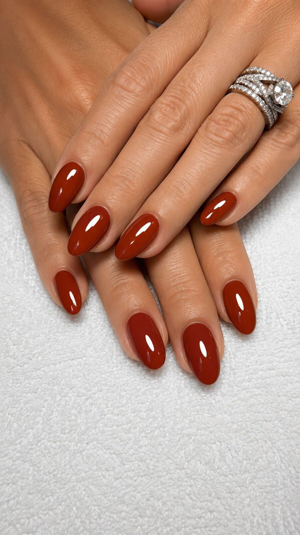 Glossy almond nails in a deep rust red